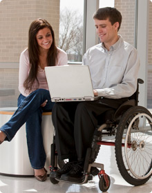 disabled man using laptop with friend